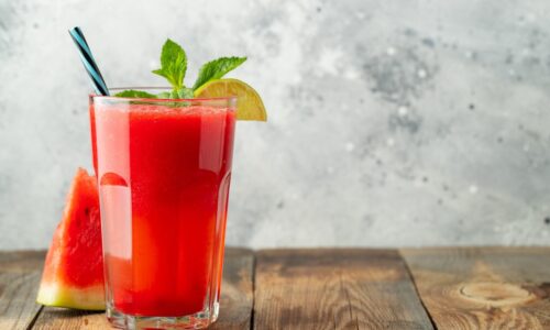 Egy pohár görögdinnyés ital citromkarikával és mentalevéllel díszítve.