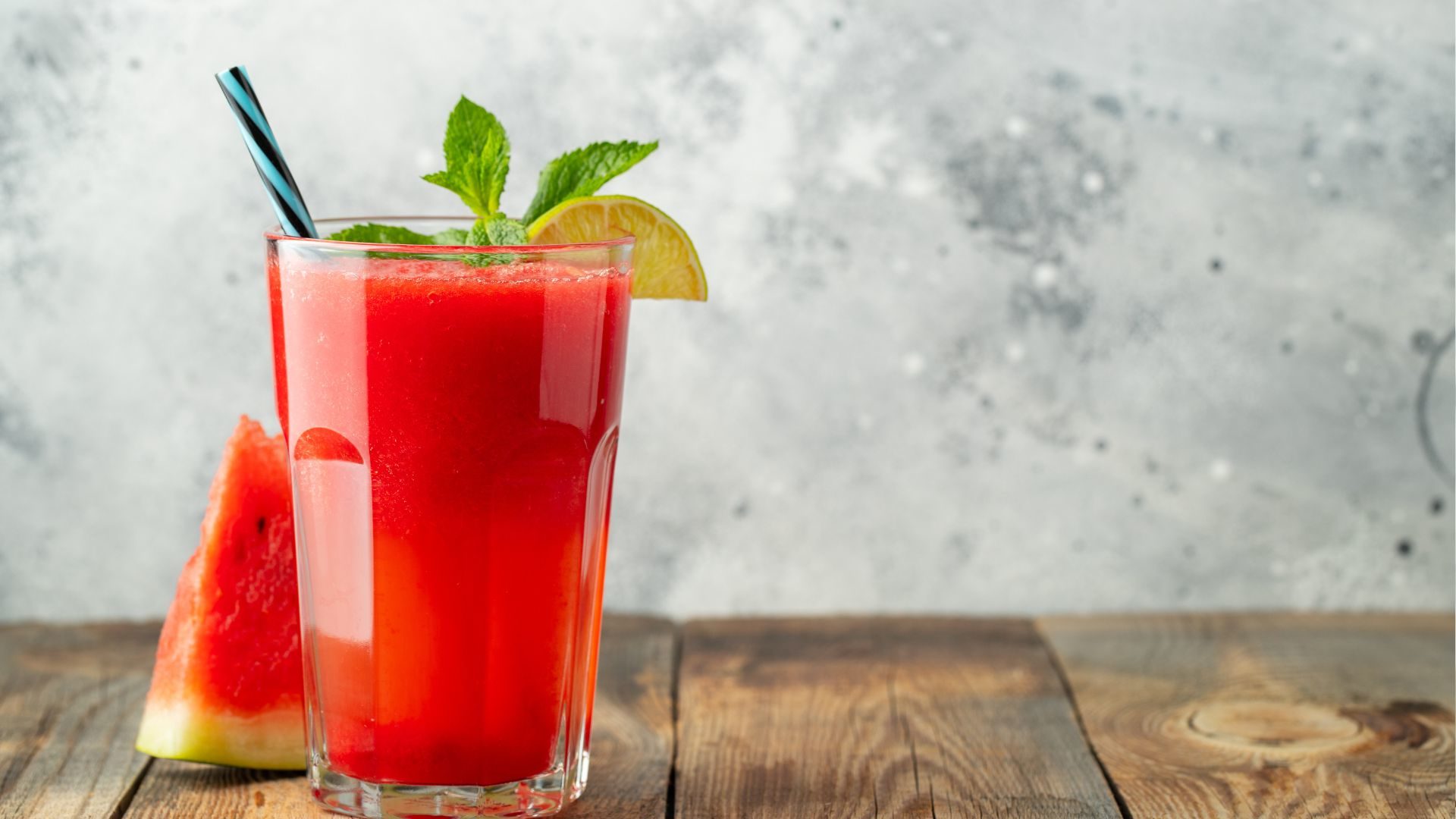 Egy pohár görögdinnyés ital citromkarikával és mentalevéllel díszítve.