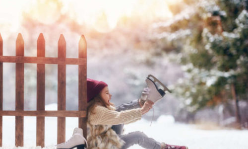 Happy child playing on a winter walk in nature. Cute little kid girl is going skate outdoors.
