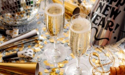 A képen két pezsgős pohár látható, körülötte sok sok dísszel.